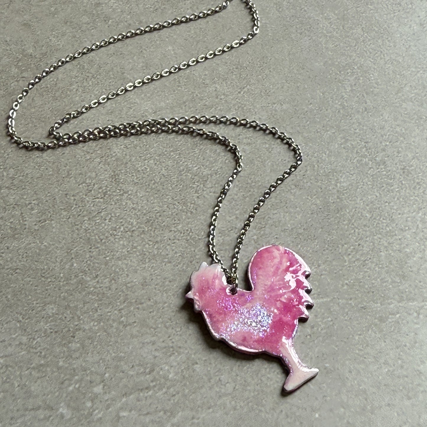 Necklace with a pink rooster-shaped pendant on a gray background